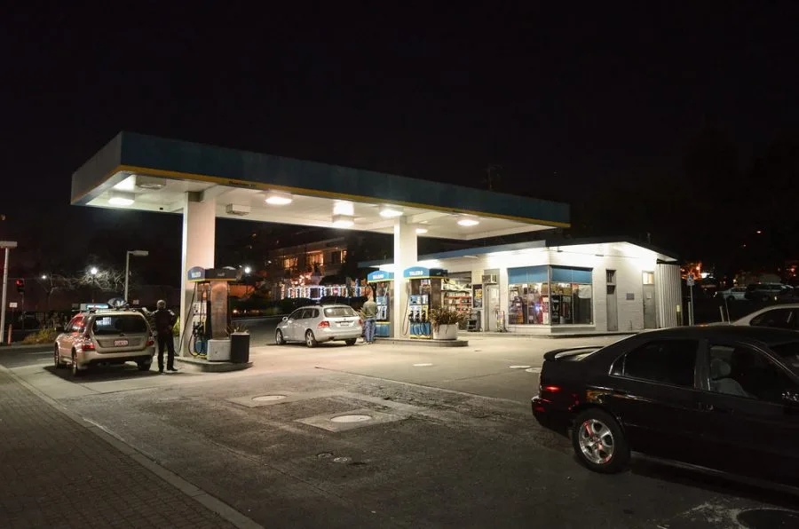 Stazione di servizio illuminata con auto alle pompe di carburante