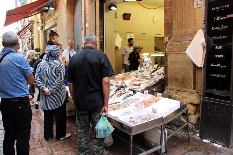 Clienti davanti a una pescheria di strada a Bologna, simbolo del commercio di prossimità