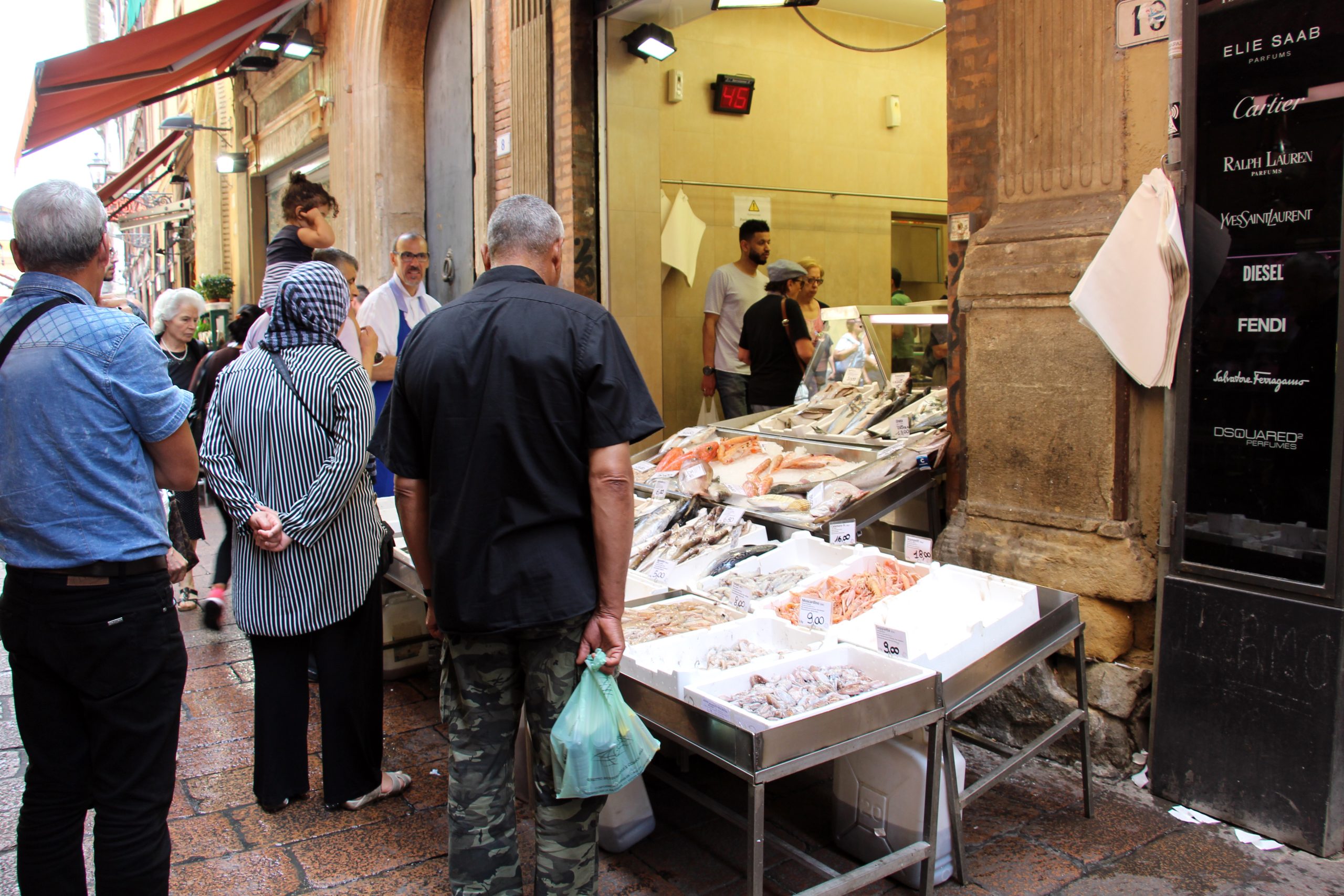 Clienti davanti a una pescheria di strada a Bologna, simbolo del commercio di prossimità