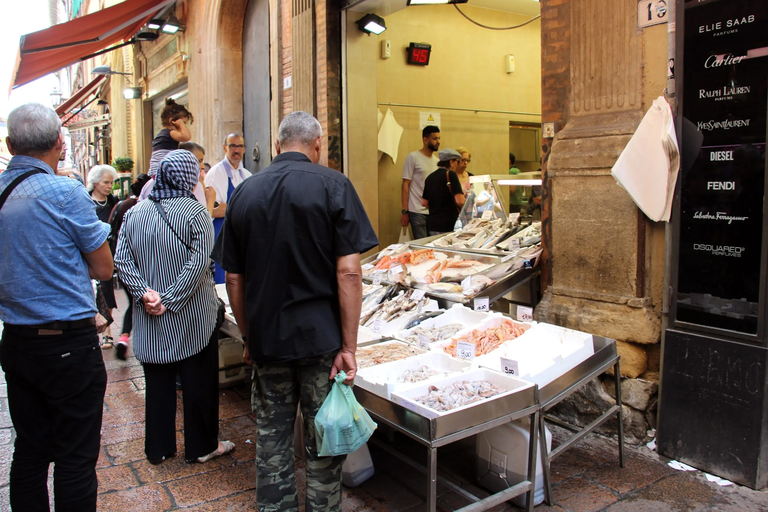 Clienti davanti a una pescheria di strada a Bologna, simbolo del commercio di prossimità