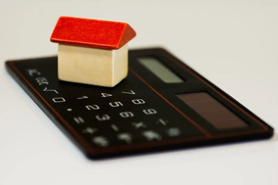Modellino di casa su una calcolatrice per il bilancio familiare