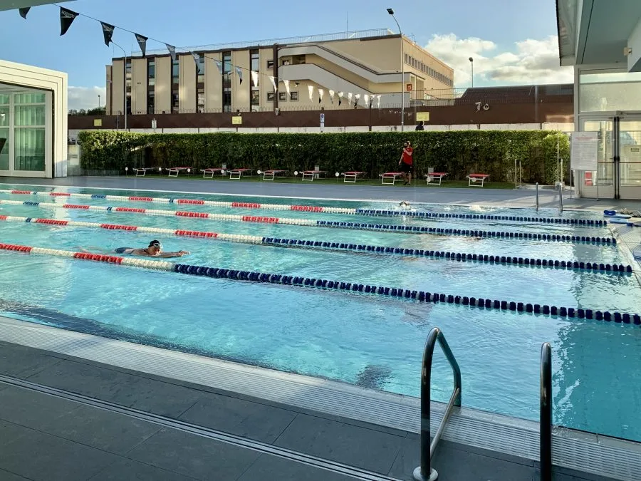 Piscina all’aperto con corsie e bagnanti, contesto di sicurezza nelle strutture natatorie