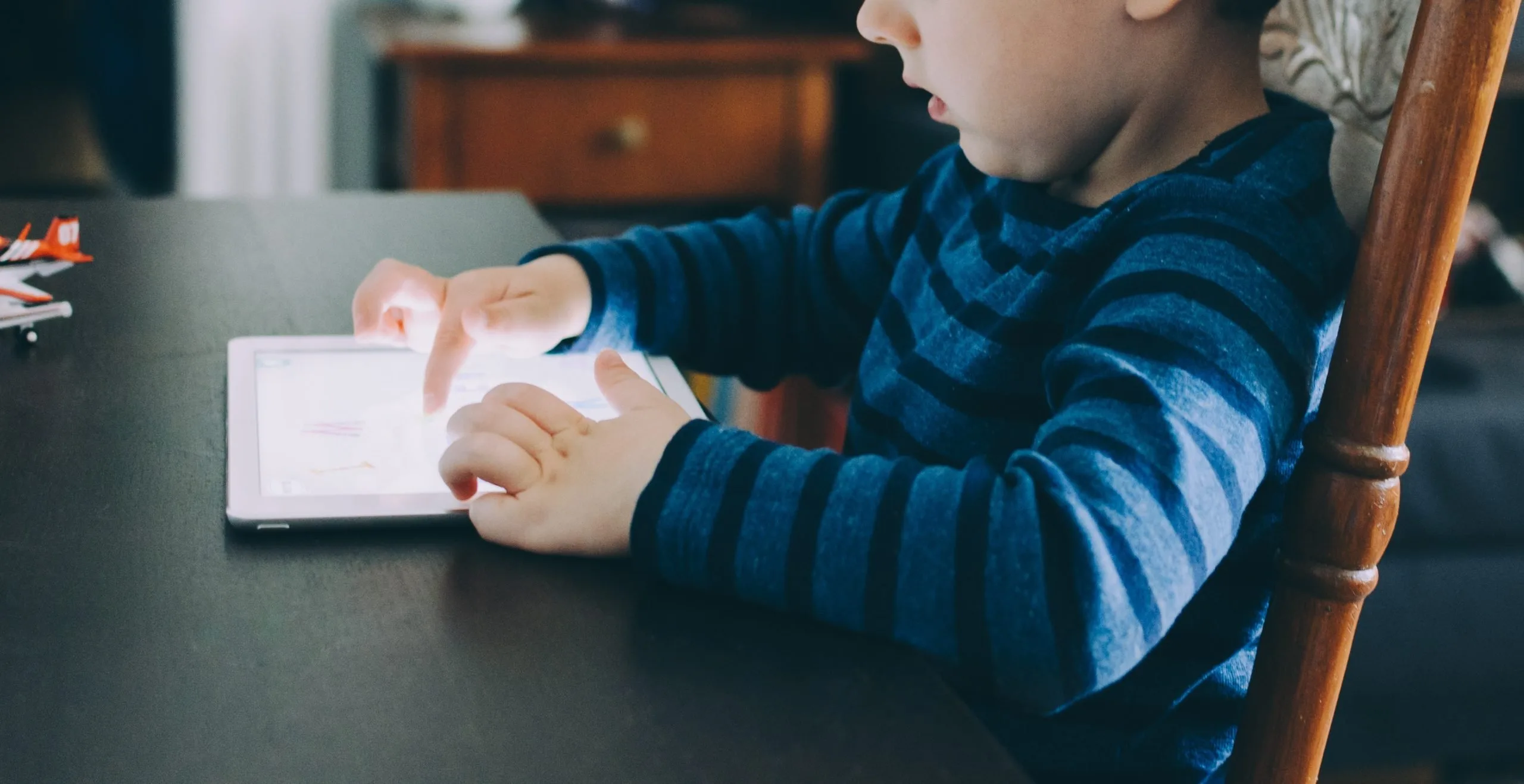 Bambino piccolo seduto al tavolo mentre usa un tablet