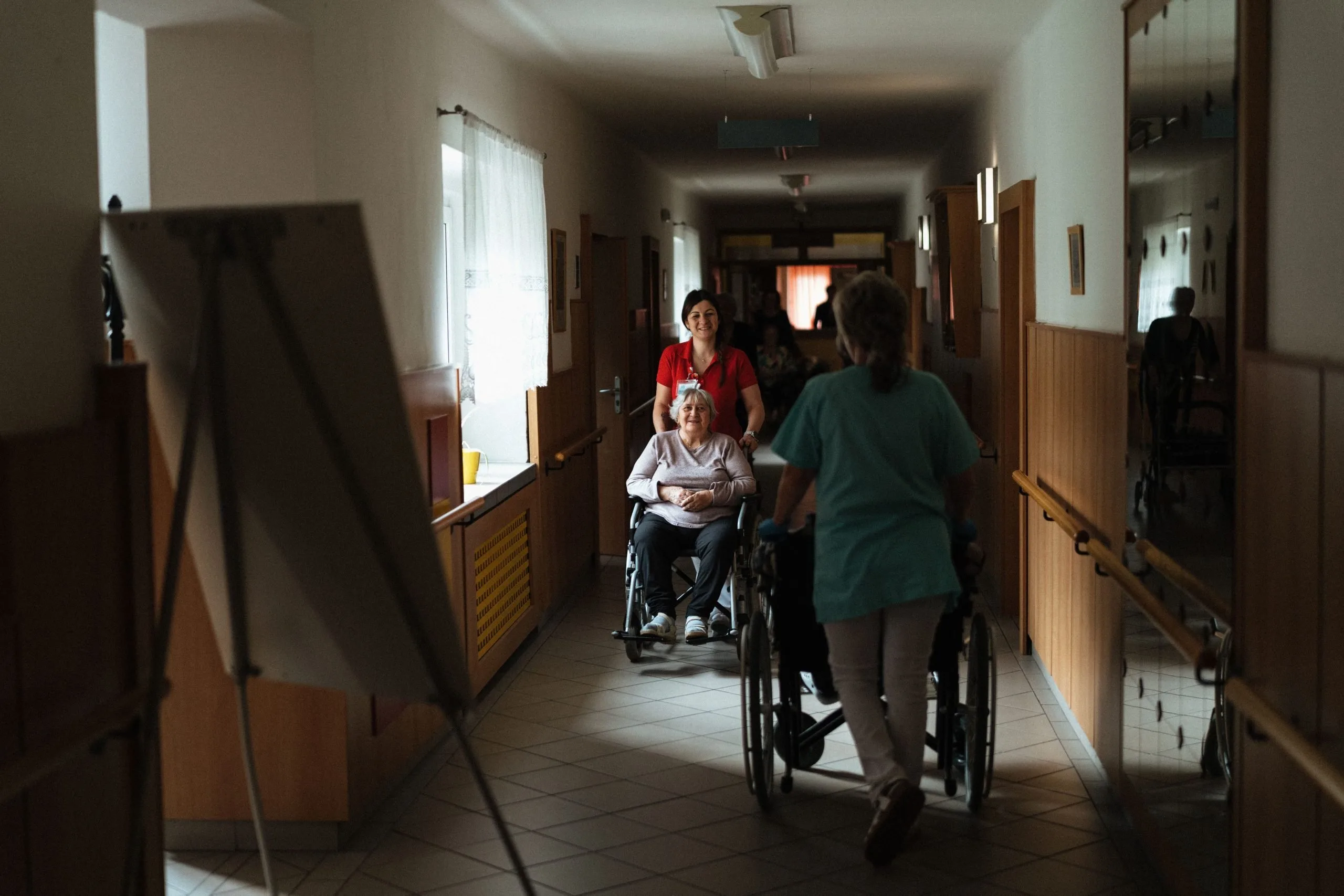 Caregiver che assistono persone anziane in carrozzina in una struttura
