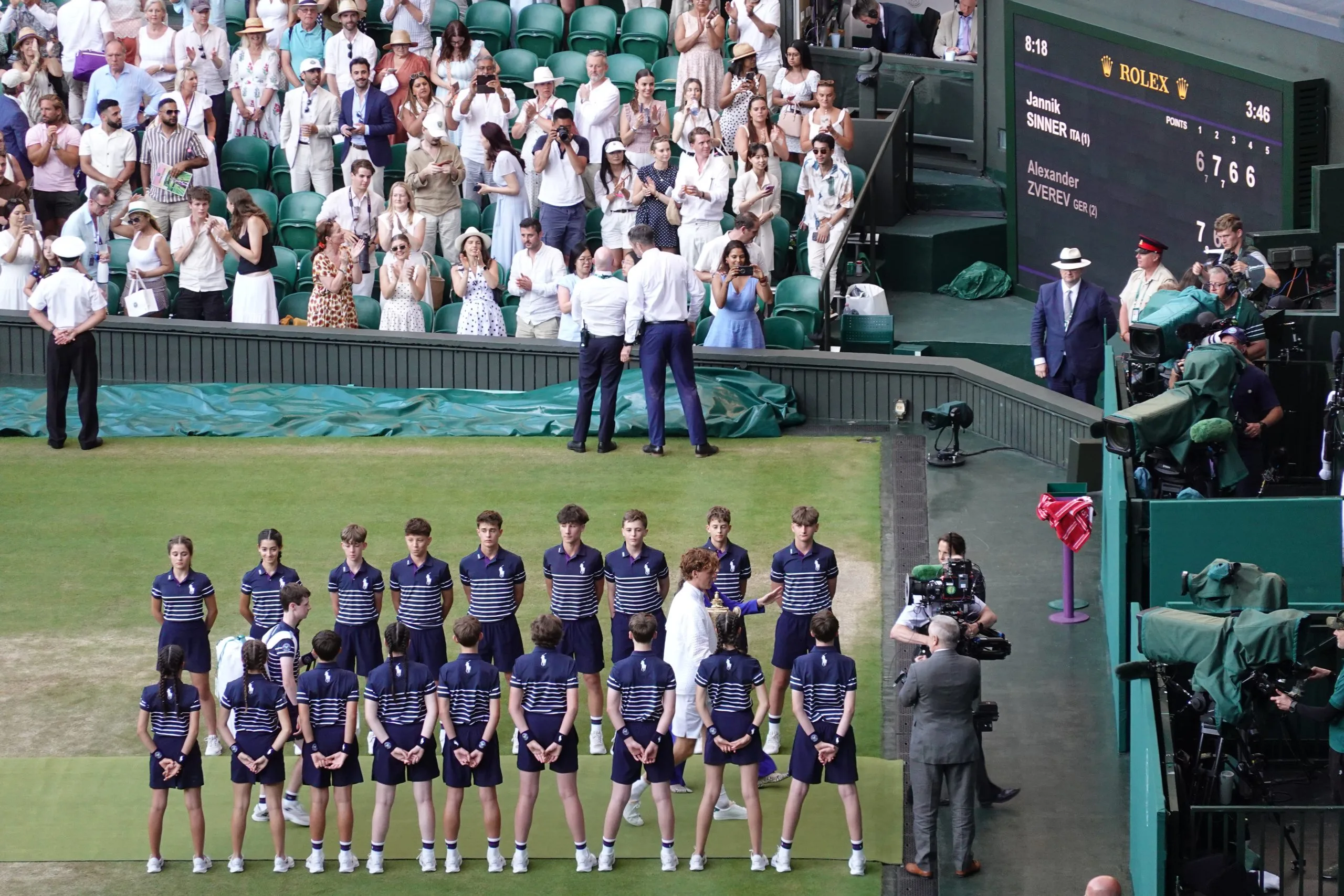 Jannik Sinner sul Centre Court dopo la finale di Wimbledon 2026 con il tabellone alle spalle