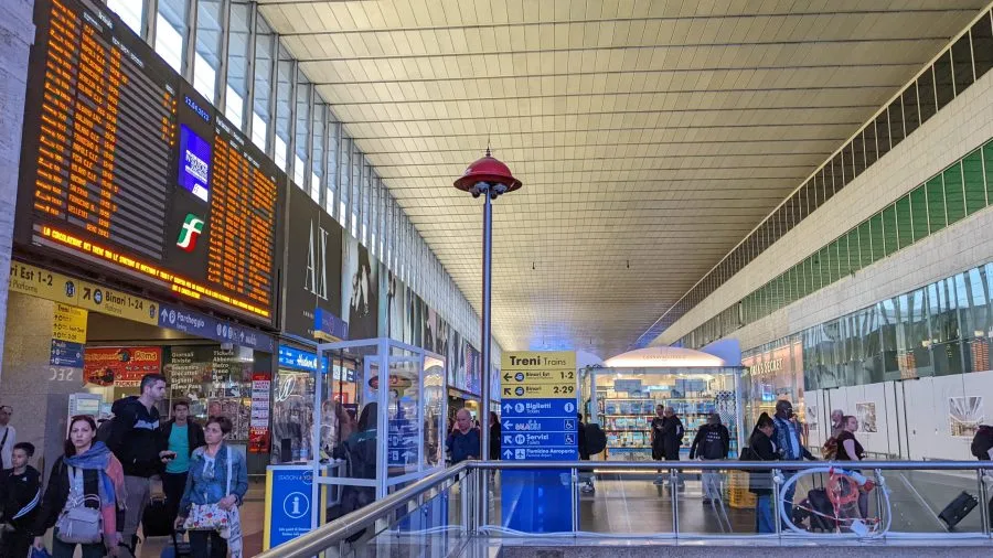 Atrio di Roma Termini con tabelloni e viaggiatori in partenza