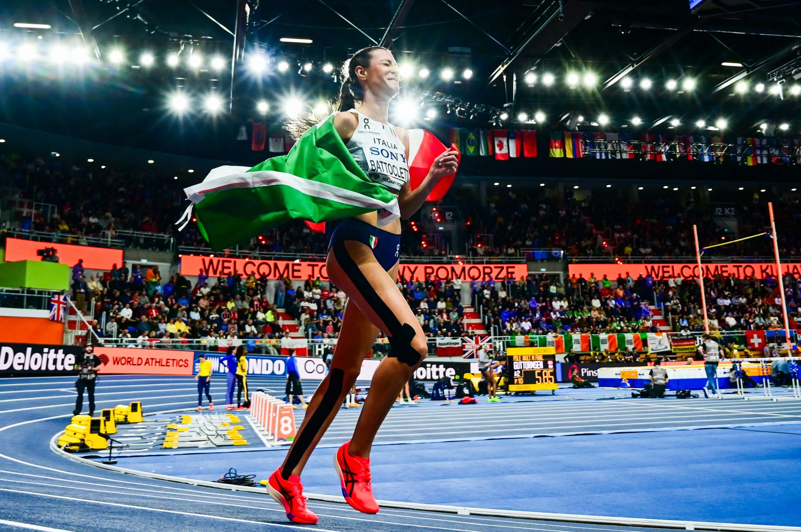 Nadia Battocletti festeggia con la bandiera italiana su una pista indoor