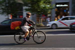 Rider Glovo in bicicletta in contesto urbano
