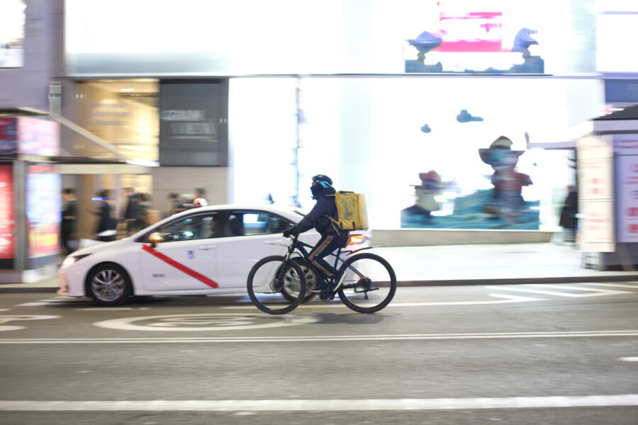 Rider Glovo con zaino giallo durante una consegna urbana