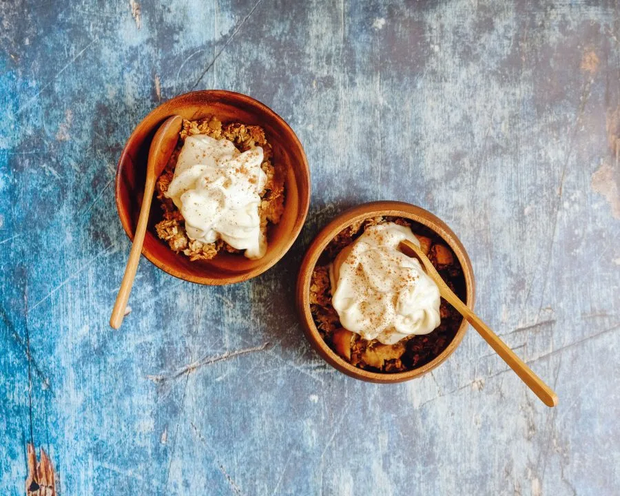 Due ciotole di granola con crema e cucchiai su un tavolo
