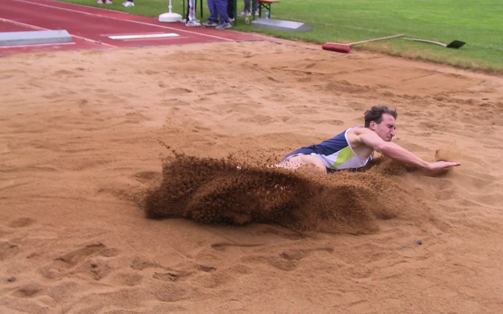 Atleta che atterra nella sabbia durante un salto in lungo