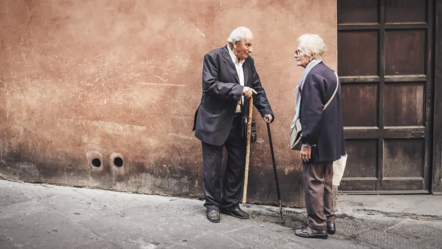 Due persone anziane conversano in una strada italiana