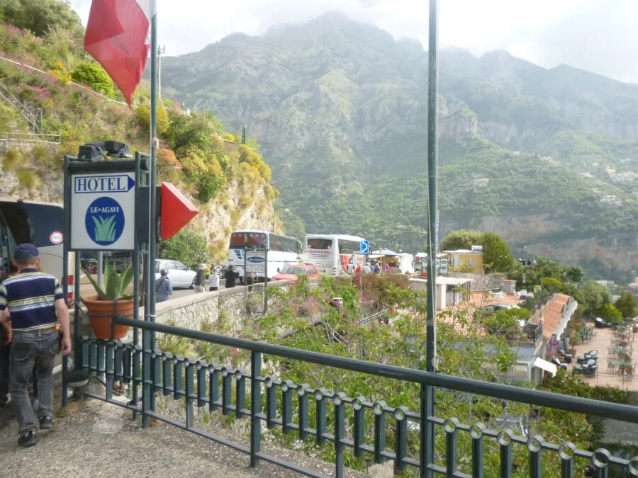 Bus e auto sulla strada costiera verso Positano con costone roccioso alle spalle