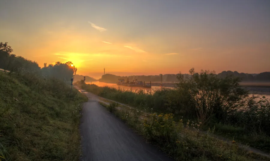 Cantiere infrastrutturale europeo lungo un canale con mezzi di lavoro