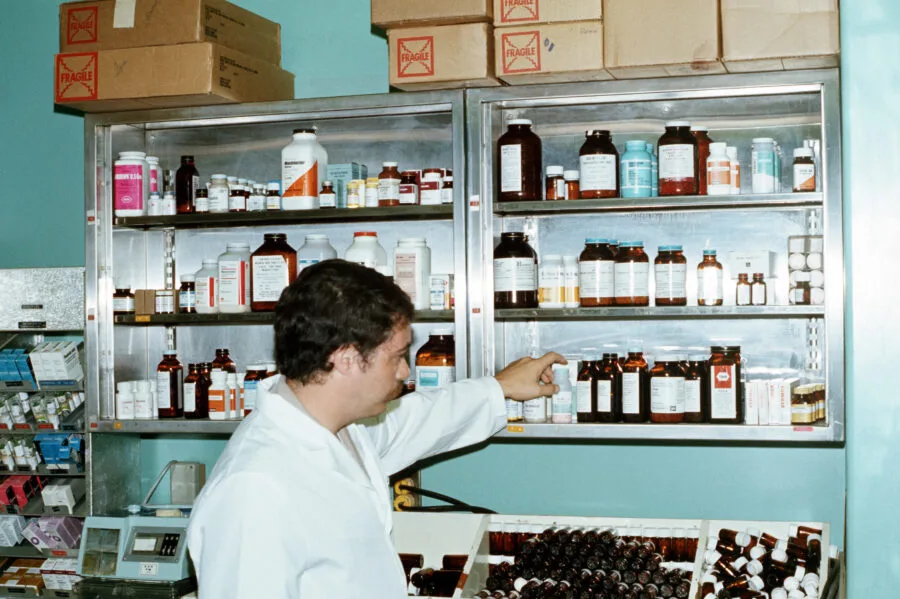 Farmacia ospedaliera con scaffali di medicinali e farmacista al lavoro