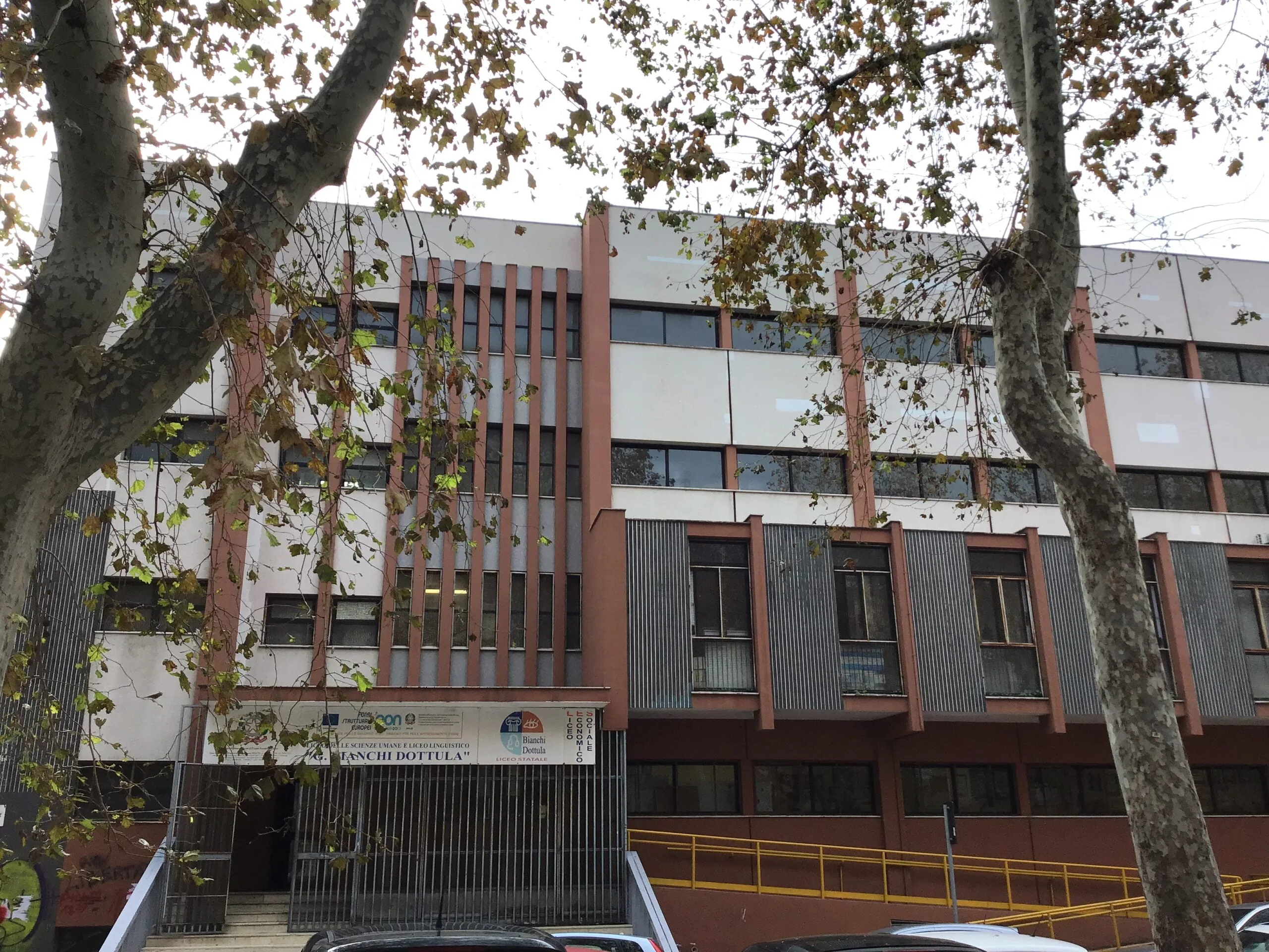 Facciata di un liceo italiano con alberi e ingresso esterno