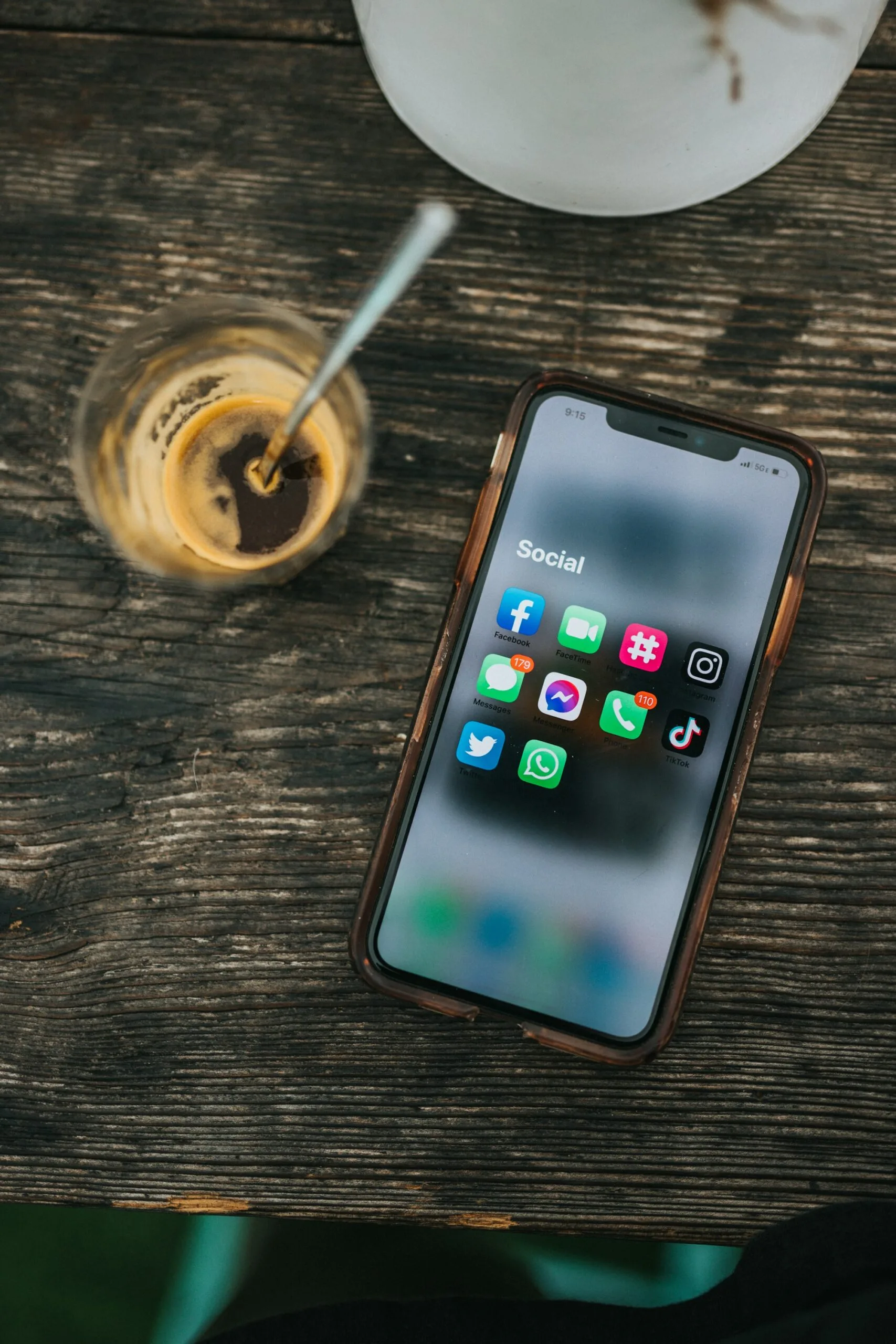Smartphone su un tavolo accanto a un caffè, con l’icona WhatsApp fra le app social