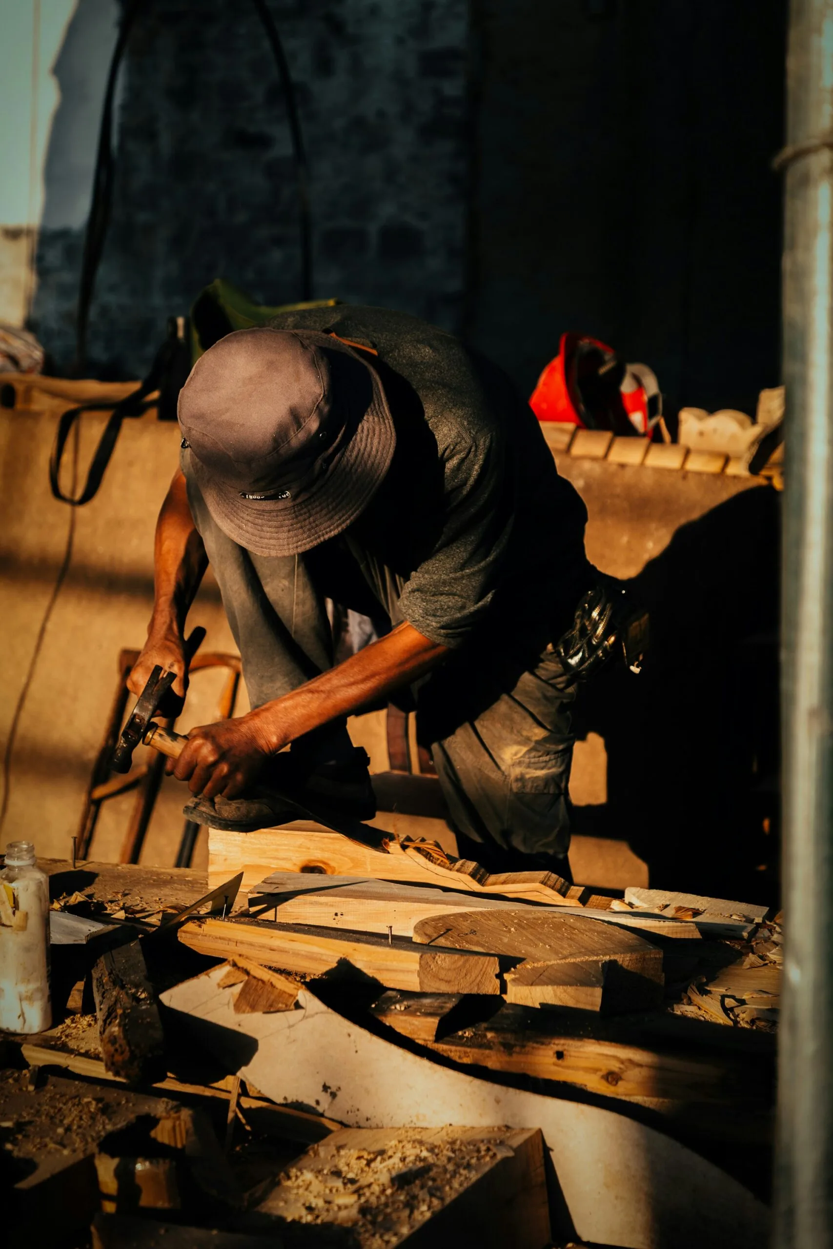 Artigiano con cappello che lavora il legno con una pialla in una bottega