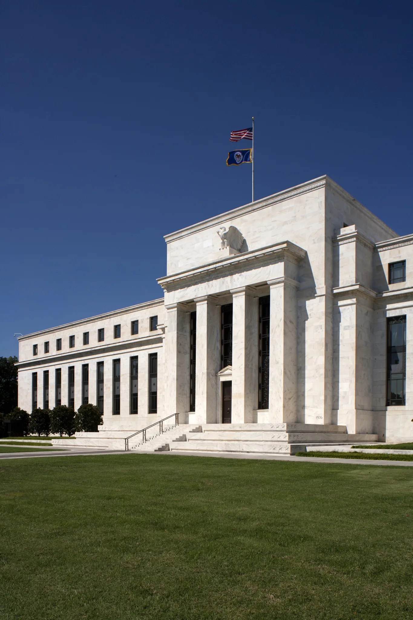 Facciata del Marriner S. Eccles Building con colonne, prato e bandiere a Washington