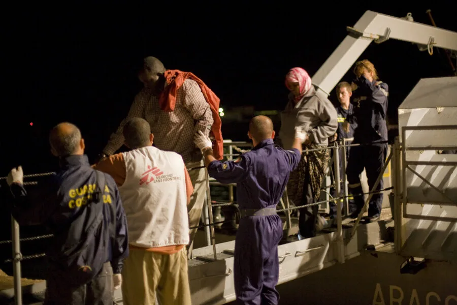 Sbarco notturno a Lampedusa con operatori sanitari e Guardia Costiera