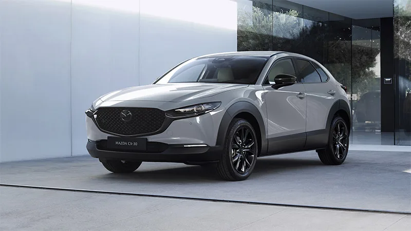 Mazda CX-30 2027 grigia davanti a un edificio, vista di tre quarti anteriore