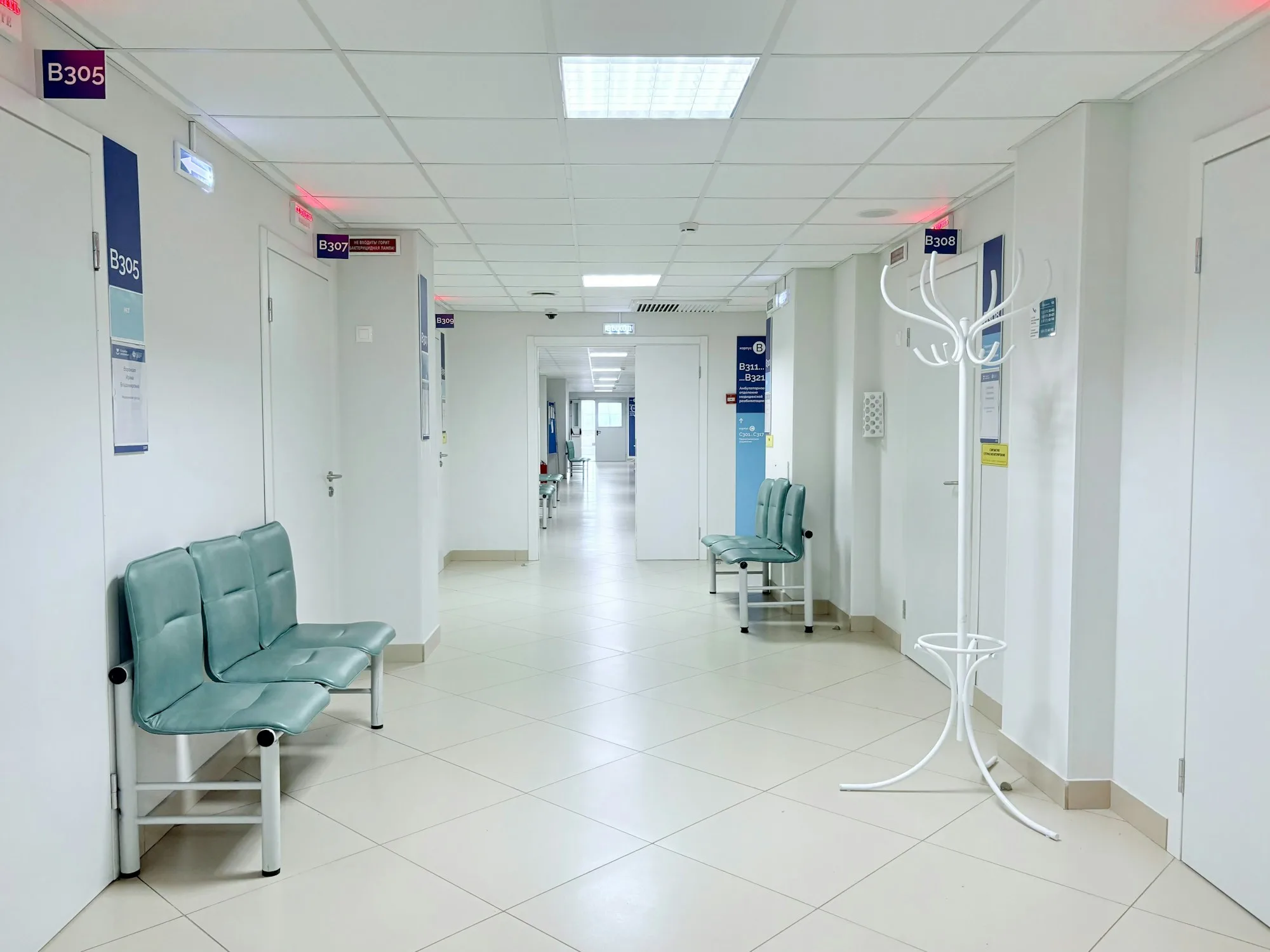 Corridoio sanitario vuoto con porte e sedute verdi lungo le pareti