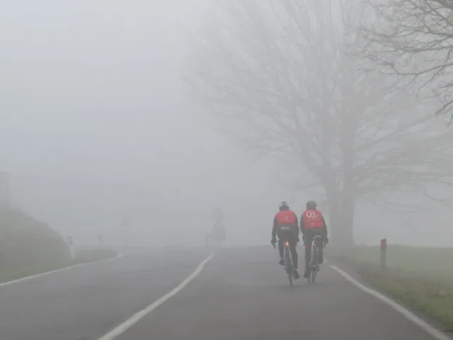 Ciclisti su una strada toscana nella nebbia