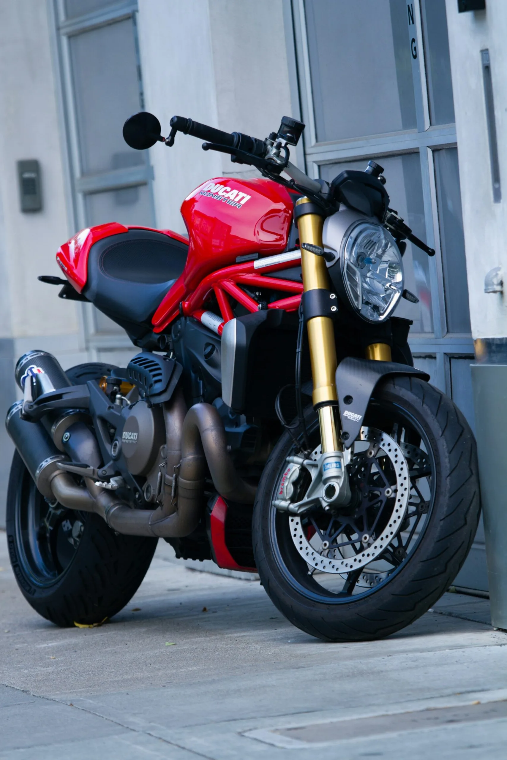 Ducati Monster rossa di una generazione precedente parcheggiata davanti a un edificio, vista anteriore di tre quarti