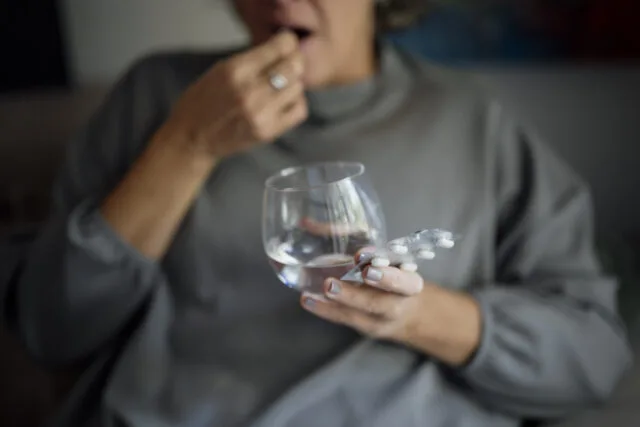 Persona che assume un farmaco con acqua, immagine illustrativa