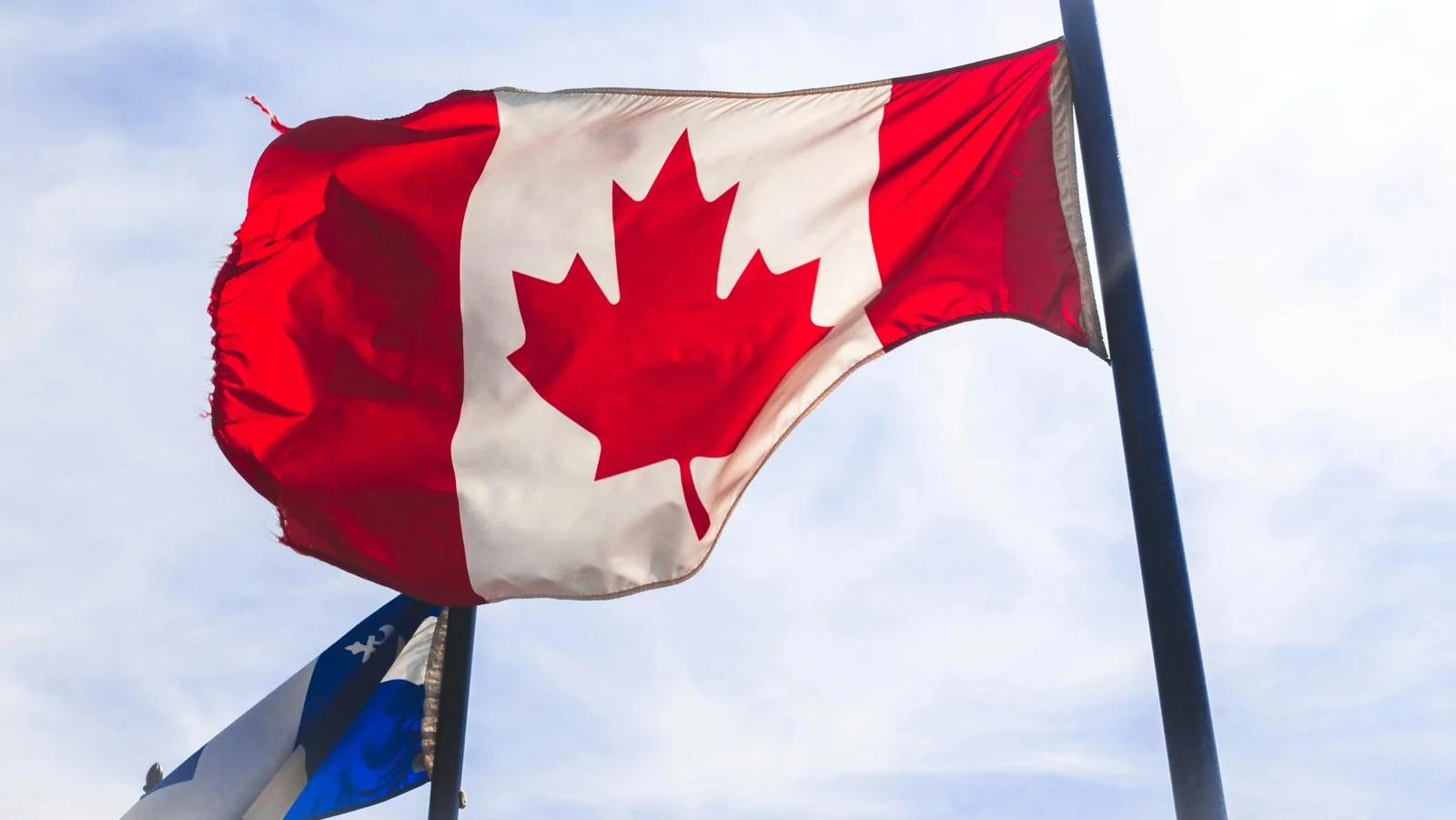 Bandiera canadese al vento e parte della bandiera del Québec a Montréal