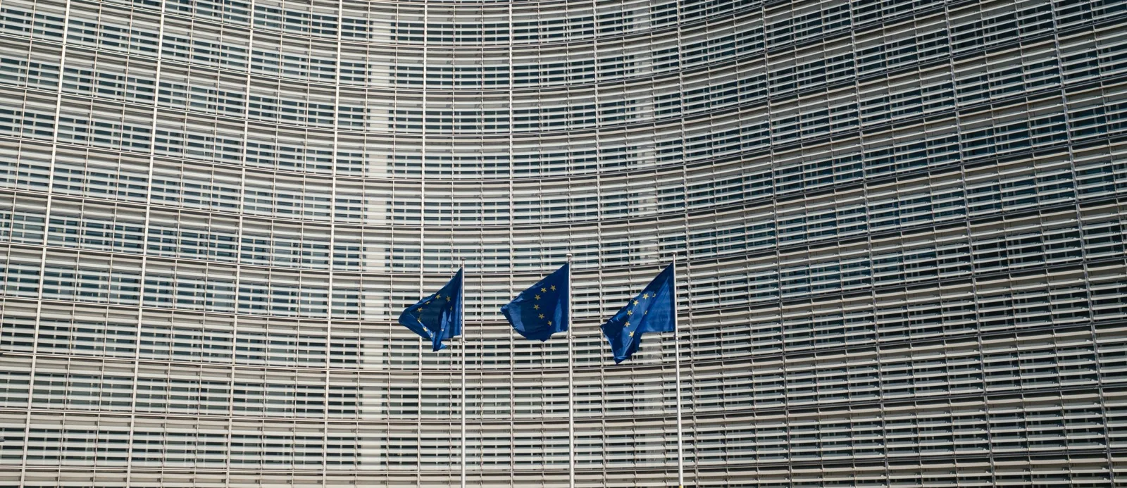 Tre bandiere dell’Unione europea davanti alla facciata della Commissione a Bruxelles