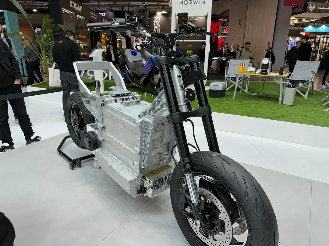 Telaio e componenti di una moto elettrica nello spazio Horwin a EICMA 2023, con visitatori sullo sfondo
