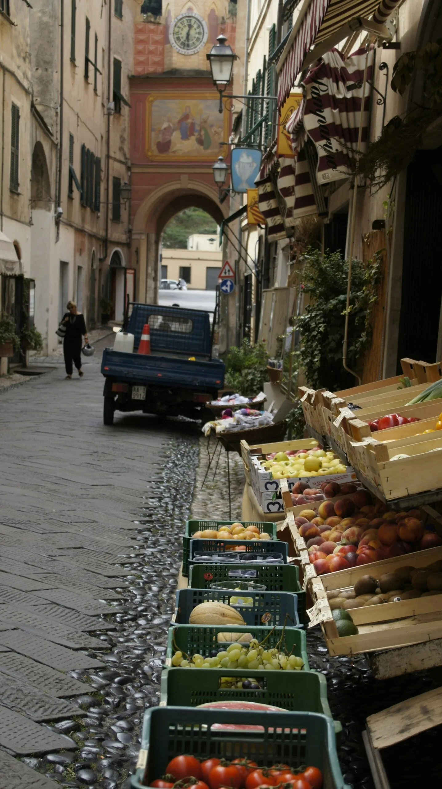 Cassette di frutta e verdura davanti a un negozio lungo una strada di Finalborgo