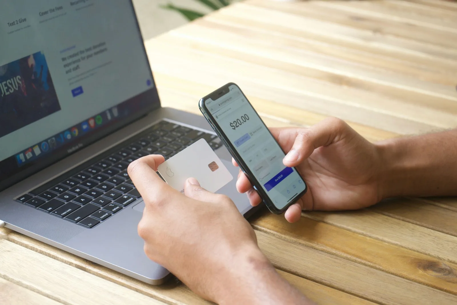 Mani con carta e smartphone davanti a un computer portatile