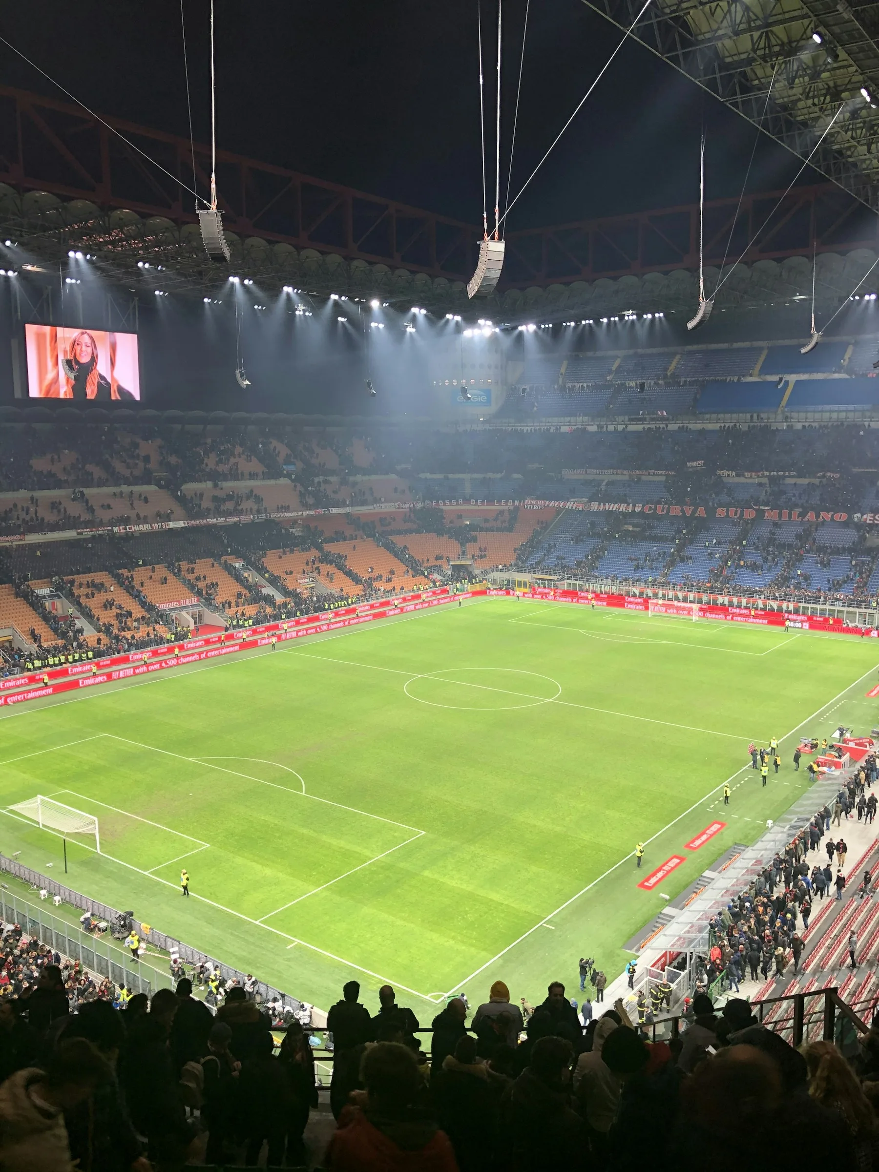 Vista dall’alto del campo e delle tribune di San Siro illuminati, con spettatori sugli spalti