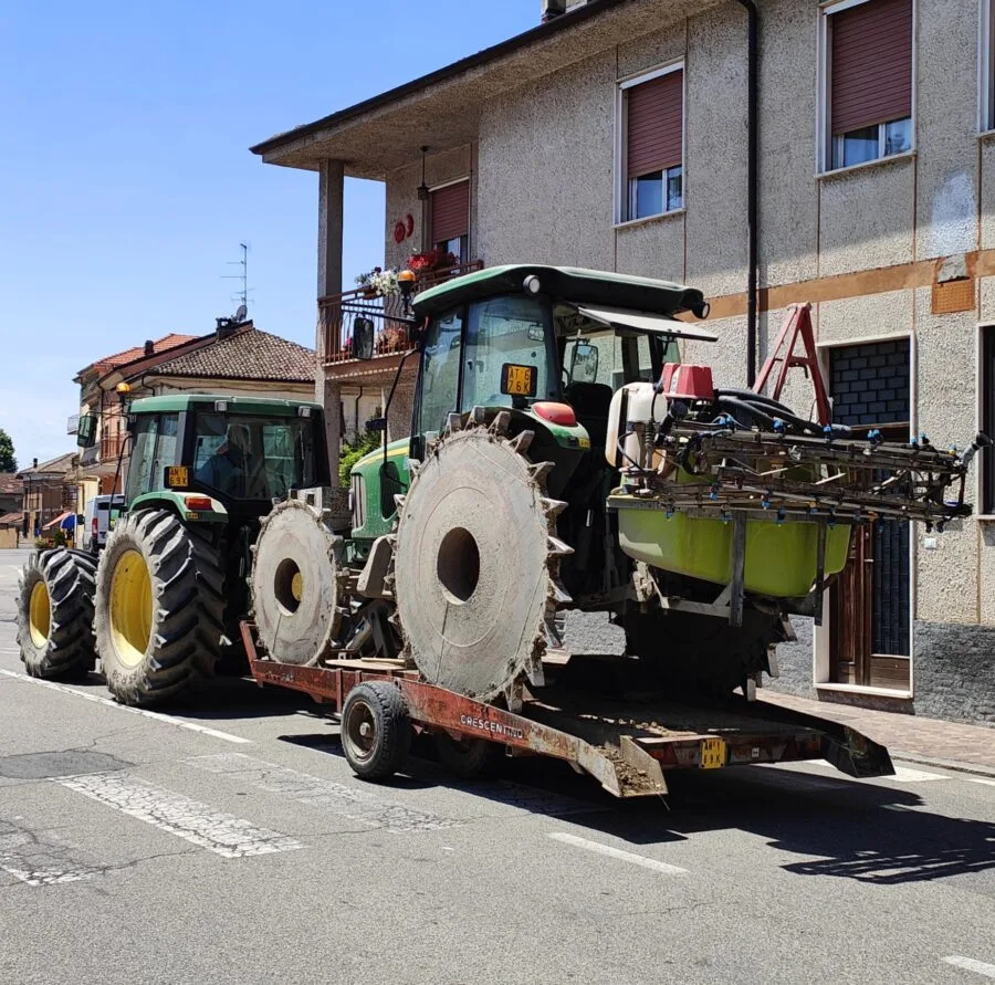 Due trattori agricoli parcheggiati accanto a una casa, uno con ruote d’acciaio da risaia