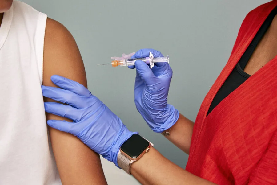 Operatore sanitario prepara una vaccinazione sul braccio di una paziente